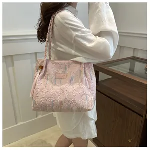 Dettaglio borsa shopper rosa trapuntata con ricami, tracolla intrecciata e nappa decorativa