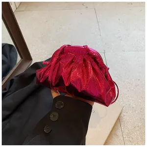 Close-up of metallic magenta pleated cloud bag with slim strap and glossy finish