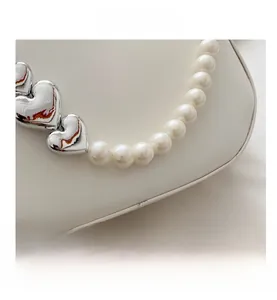 Detail of white leather heart-accented handbag with elegant large pearl handle