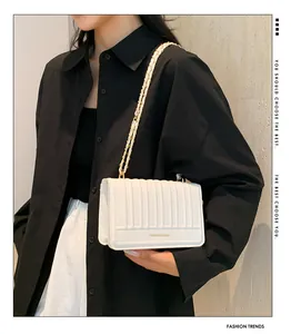 Gros plan du sac bandoulière blanc plissé avec chaîne dorée porté par un mannequin