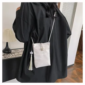 Detail of white marble pattern phone bag with large pearl clasp and long silk tassel