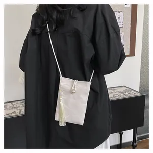 Detail of marble texture crossbody phone bag featuring a pearl clasp and long silk tassel