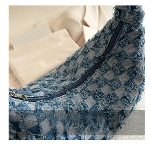 Detail of blue and white checkered denim crescent bag with frayed fringe edges