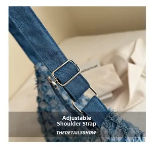 Detail of adjustable denim shoulder strap with silver buckle on blue crescent bag