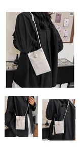Detail of beige textured crossbody phone bag with pearl buckle and elegant tassel