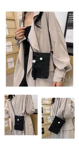 Detail of black pleated crossbody phone bag with a large pearl and long fringe tassel