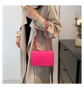 Détail du sac à bandoulière en similicuir rose vif avec texture verticale et chaîne