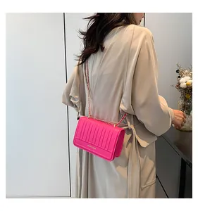 Sac bandoulière fuchsia moderne avec texture à rayures verticales et chaîne dorée sur mannequin