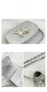 Detail view of silver mini saddle bag featuring metal butterfly clasp and magnetic closure