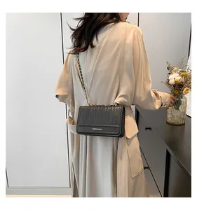 Détail d'un sac à bandoulière noir matelassé avec chaîne dorée et logo élégant
