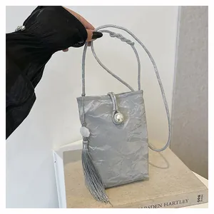 Detailed view of silver pleated phone bag with pearl closure and long tassel charm