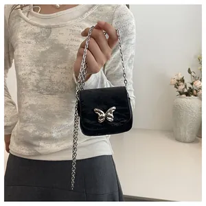 Close-up of black pleated mini bag with a silver butterfly buckle and chain strap