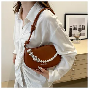 Detail of brown half-moon bag with pearl heart chain and Fashion & Bags print