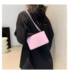 Gros plan d'un sac sous le bras rose matelassé avec une bandoulière chaîne sur modèle