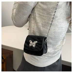 Close-up of black wrinkled leather mini crossbody bag with silver bow hardware and chain strap
