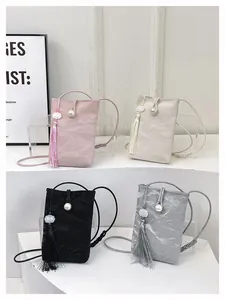 Detail of crossbody phone bags with tassel accents and pearl clasps in four pastel colors