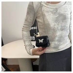 Close-up of black mini saddle bag with silver butterfly chain and crinkled texture leather