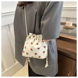 Détail du sac seau en velours côtelé blanc avec imprimés fraises rouges et vertes