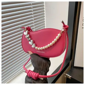Detail of rose pink handbag featuring pearl and silver heart chain with knotted strap