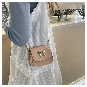 Detail of pink mini crossbody bag with silver bow ornament and metallic chain strap
