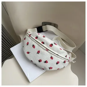 Detail van de witte corduroy crossbody tas met geborduurde aardbeien en verstelbare riem