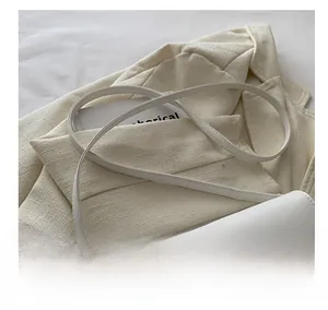 Détail de la bandoulière réglable et boucle V dorée sur sac en cuir blanc