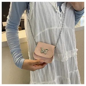 Detail of pink mini saddle bag featuring silver butterfly chain and faux leather texture