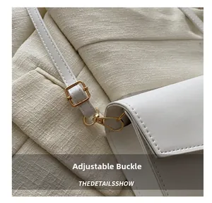 Détail de la boucle dorée réglable sur un sac à bandoulière en cuir blanc lisse