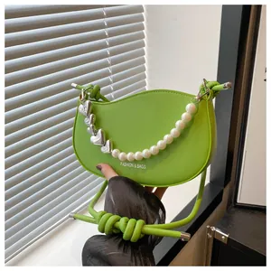 Detailed close-up of green crescent bag featuring heart metal and pearl decorative chain