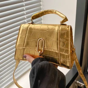 Close-up of gold crocodile-patterned mini handbag with U-shaped buckle and metallic finish