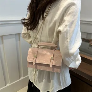 Pink marble texture crossbody bag with gold chain strap and top handle in a lifestyle shot