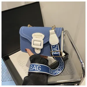 Nahaufnahme der blauen Denim-Umhängetasche mit weißer Schnalle und gewebtem Trageriemen