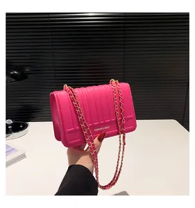 Détail du sac bandoulière rose fuchsia avec matelassage vertical et chaîne en métal doré