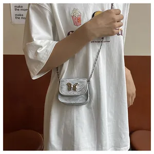 Detail of silver mini crossbody bag with wrinkled texture and metal bow buckle strap