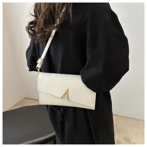 Détail du sac à bandoulière en cuir blanc crème avec rabat asymétrique et boucle dorée en V