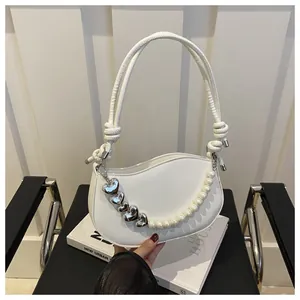 Detail of white heart-shaped handbag with silver heart studs and a delicate pearl chain