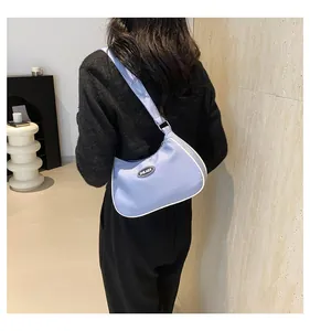 Detail view of light blue crescent shoulder bag with white trim and logo on model