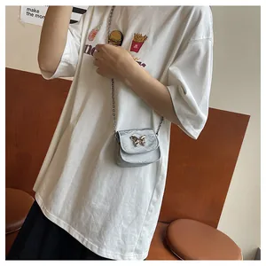 Detailed view of silver mini crossbody bag with golden butterfly buckle and chain strap
