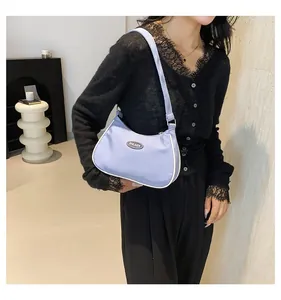 Close-up of lilac hobo bag showing metallic logo plate and white contrast stitching