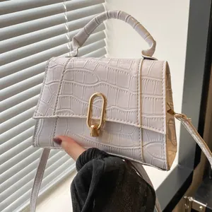 Detail of white crocodile pattern leather handbag with gold oval twist lock and handle