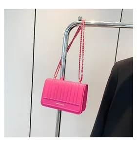 Détail du sac bandoulière matelassé rose rouge avec chaîne dorée et finition cuir texturé