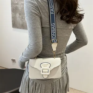 Weiße Umhängetasche mit blauem Webriemen in modischer quadratischer Form am Modell