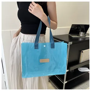 Macro shot of light blue transparent PVC tote with dark blue straps and brand leather patch