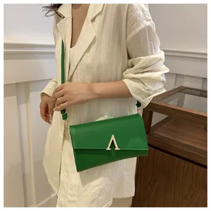 Gros plan du sac à bandoulière vert vif avec un fermoir métallique doré en forme de V