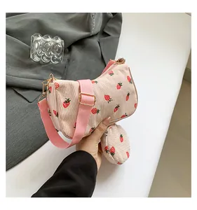 Detalle del bolso de pana rosa con estampado de fresas y un pequeño monedero redondo a juego