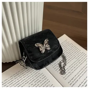 Detail of black pleated mini crossbody bag with silver bow ornament and chain strap