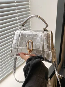 Close-up of silver crocodile embossed faux leather handbag with golden U-shaped clasp