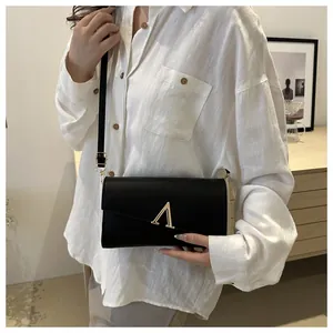 Détail du sac bandoulière en cuir noir avec logo A doré et fermeture à rabat enveloppe