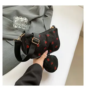 Detalle de bolso hobo de pana negra con estampado de fresas y pequeño monedero redondo