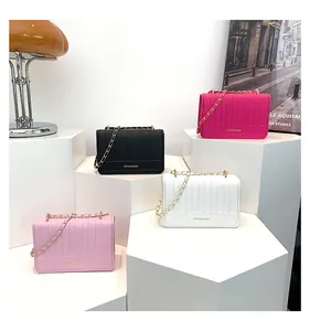 Détail des sacs matelassés en rose, noir et blanc sur des supports géométriques élégants